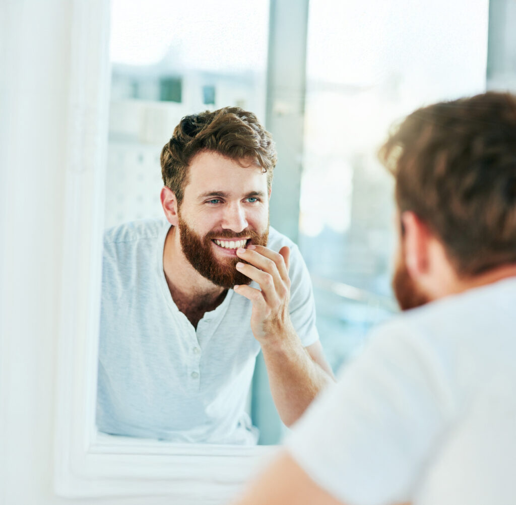 Cropped shot of a handsome young man looking at his teeth in the bathroom mirror