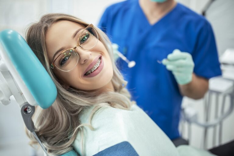 Beautiful young woman with braces having dental treatment at dentist's office